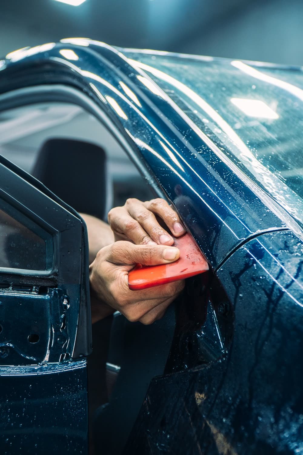 Close-up of a technician applying and smoothing protective film by hand against a vehicle surface, placeholder photography (not Hydro Shield client work)