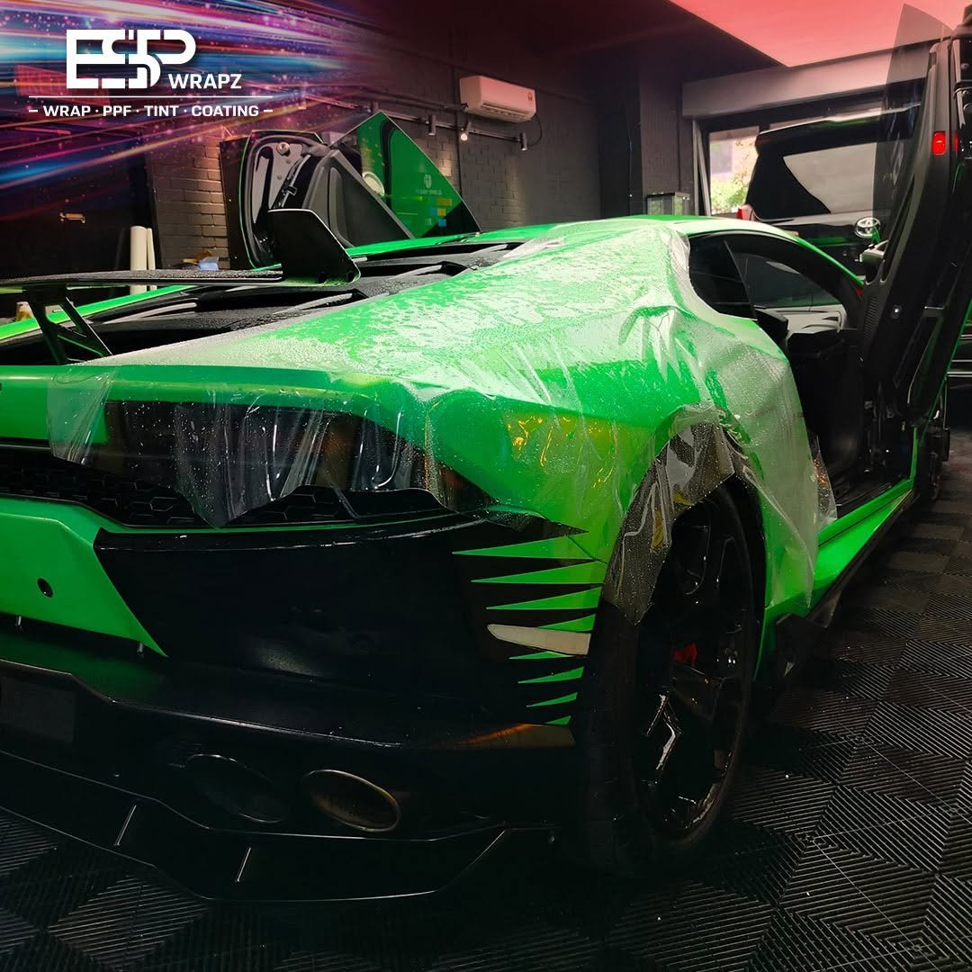 Paint protection film being applied to the front of a green Lamborghini Huracan with the door open