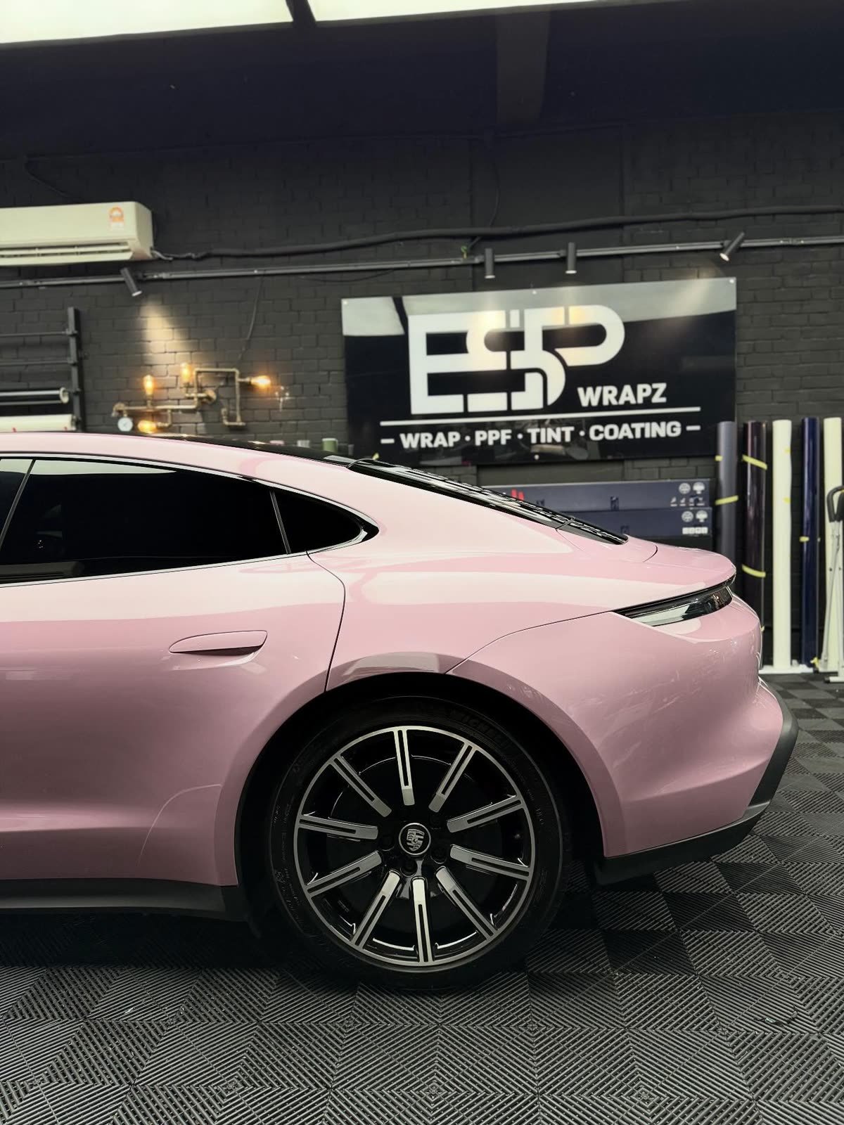 A pink Porsche Taycan, rear three-quarter view in front of the large ESP Wrapz workshop sign