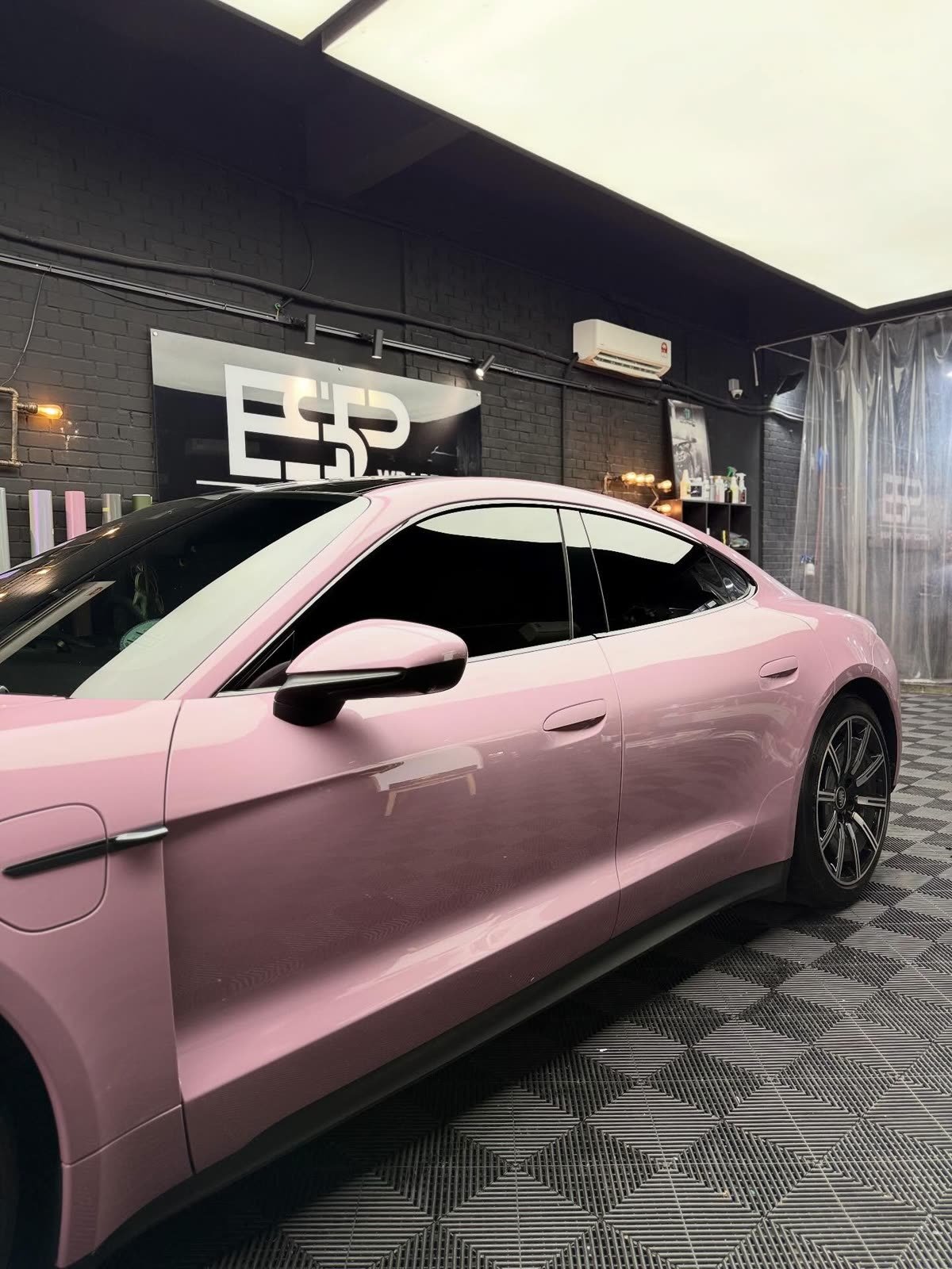 A pink Porsche Taycan, side profile view inside the ESP Wrapz workshop
