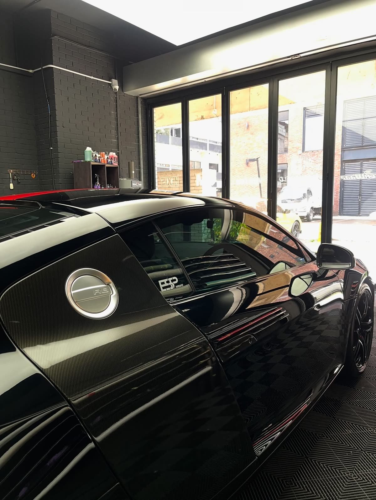 A black Audi R8 with a carbon fibre fuel cap surround and an ESP Wrapz decal on the rear window, side profile